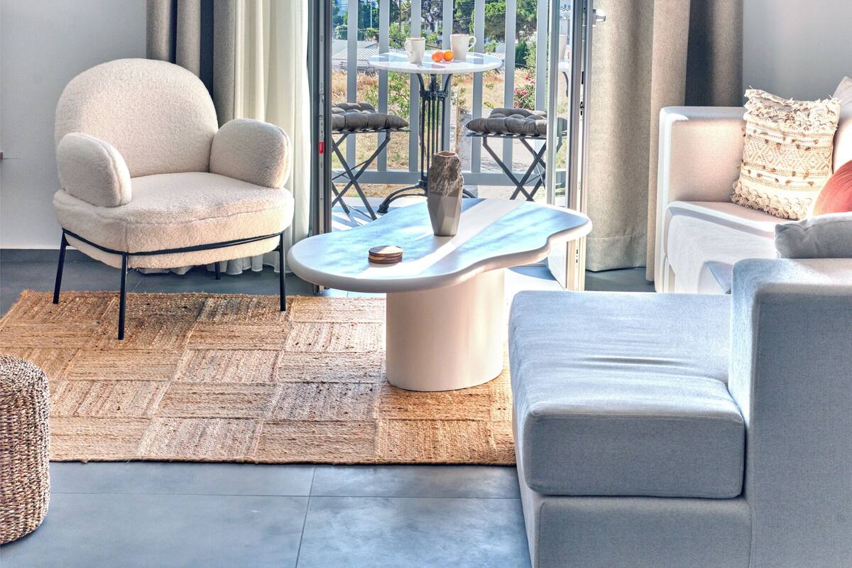 A modern living room with a view of the sea, a round coffee table, and two sofas.