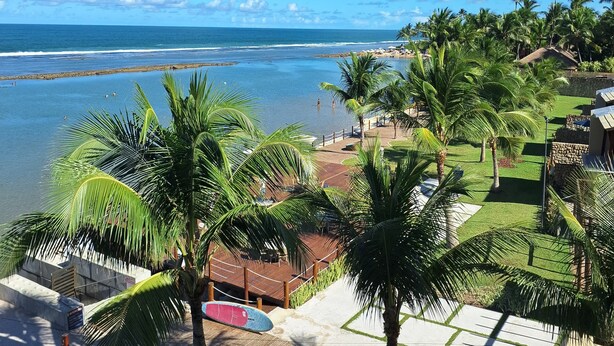 A resort with a view of the ocean, palm trees, and a beach area. - 2 bedroom apartment in Ipojuca - PE (Ipojuca - PE)