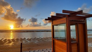 A wooden structure with a glass enclosure overlooking a beach at sunset. - 2 bedroom apartment in Ipojuca - PE (Ipojuca - PE)