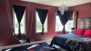 Une chambre à coucher avec un lit, un fauteuil suspendu et un lustre.