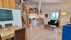 Un grand espace de vie comprenant un coin repas avec une table, un canapé et une cuisine avec un escalier.