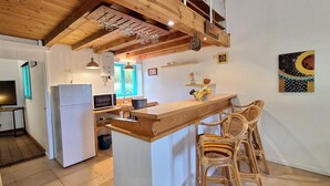Une cuisine avec un îlot central en bois, des tabourets de bar, un réfrigérateur, un four à micro-ondes et une fenêtre donnant sur un beau paysage.