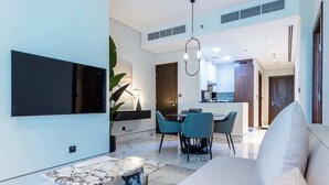 A modern living room with a marble coffee table, a sofa, and a dining area with chairs. - 1 BR in J One Tower 5 minutes from Dubai Mall (Dubai)