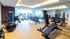 A spacious gym with various exercise equipment, including treadmills, dumbbells, and weight machines. - 1 BR in J One Tower 5 minutes from Dubai Mall (Dubai)