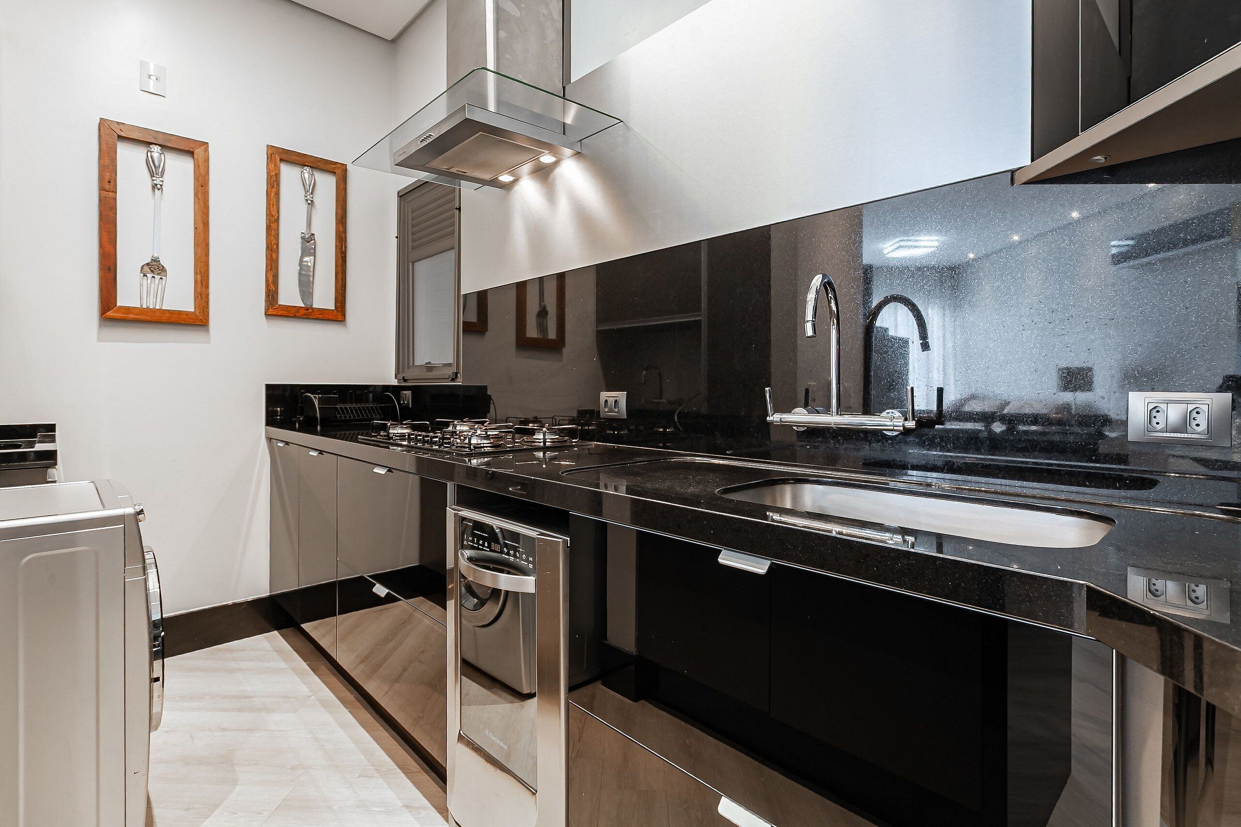 Een moderne keuken met roestvrijstalen apparatuur, een dubbele spoelbak en houten lijstwerken aan de muur.