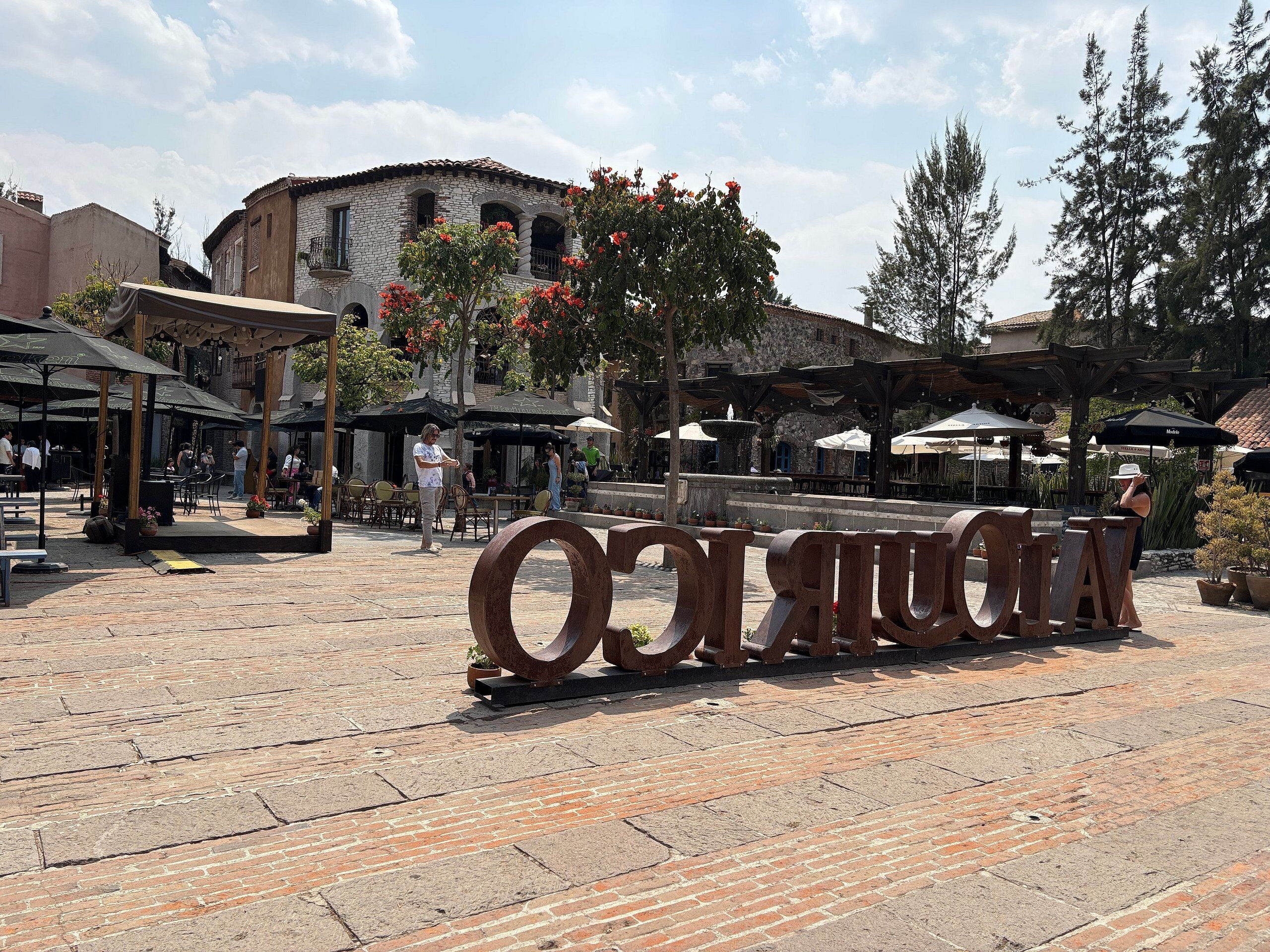 Un cortile con pavimento in pietra, posti a sedere all'aperto e un'ampia scultura in metallo.