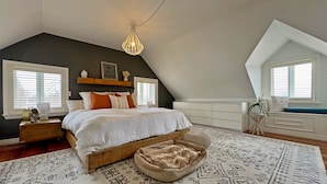 Una camera da letto con un letto grande, una testiera in legno, una lampada a sospensione e un tappeto decorato.