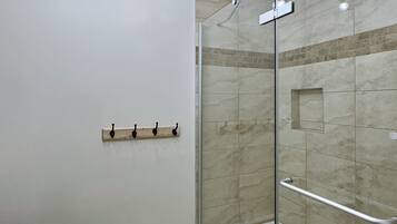 Een moderne badkamer met een douchecabine van glas, een wit toilet en een plafondlamp.