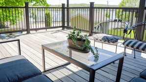 A wooden deck with outdoor furniture, including a table and chairs, and a potted plant.
