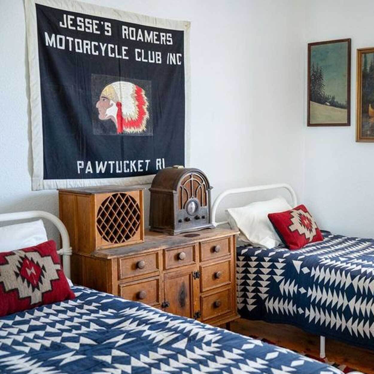 Ett rum med två sängar, en gammal radio och en väggdekoration.