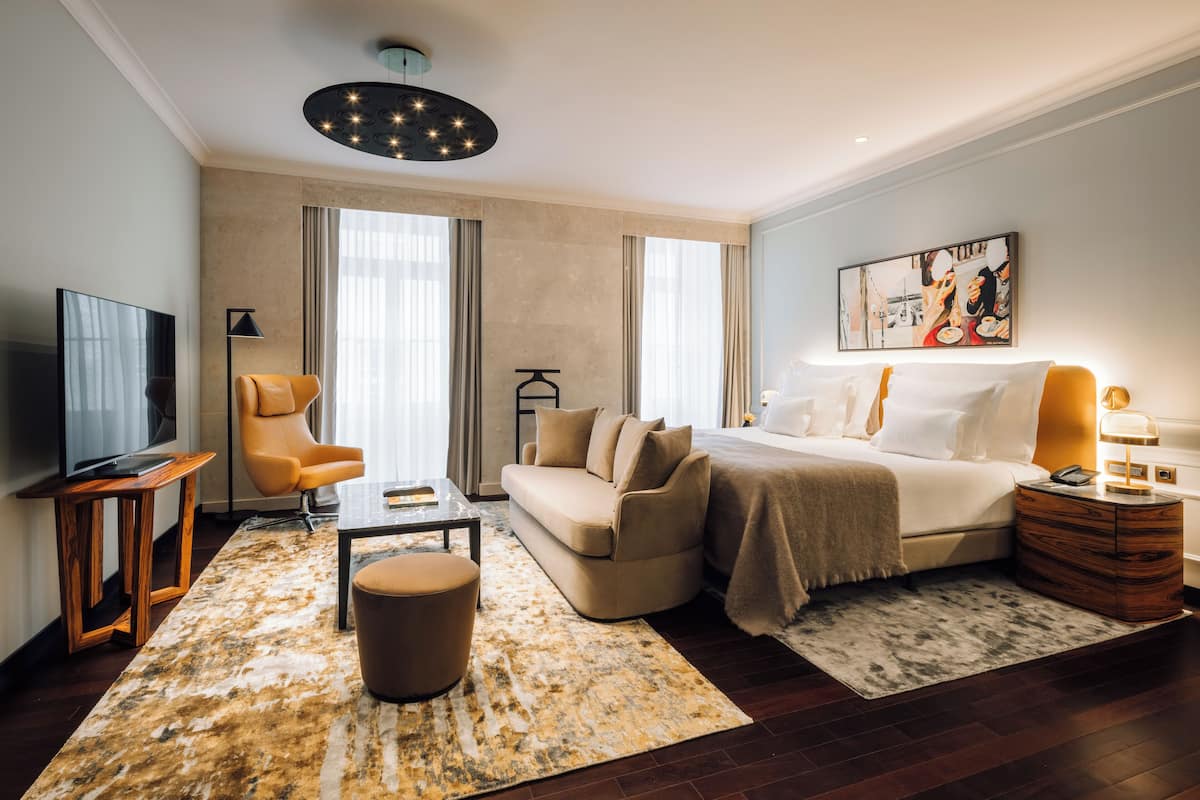 Una habitación de hotel moderna con una cama grande, un sofá, un televisor y una mesa de centro.