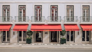 A building with multiple windows and balconies, featuring red awnings and a tiled ground floor.