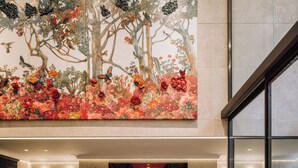 A lobby with a large floral mural, seating area, and a view through a glass partition.