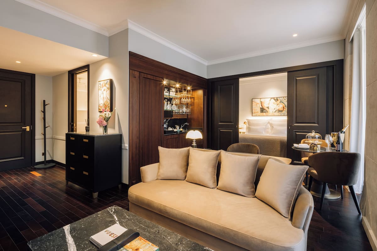 Una sala de estar moderna con un sofá color beige, muebles de madera oscura y una mesa de centro de mármol.