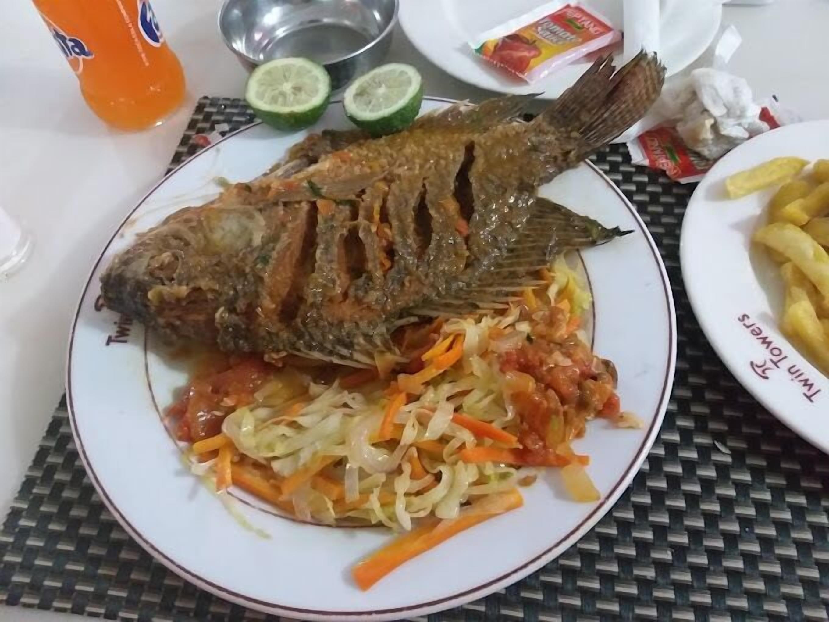 Een bord met een hele gebakken vis, een portie coleslaw en frieten.