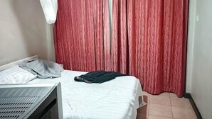 A bedroom with a bed, a desk, and a red curtain. - Hotel Twin Towers Homa Bay (Homa Bay)