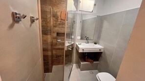Un bagno moderno con cabina doccia in vetro, lavandino bianco e water.