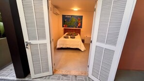 Una camera d'albergo con un letto, un quadro appeso al muro e una finestra con persiane.