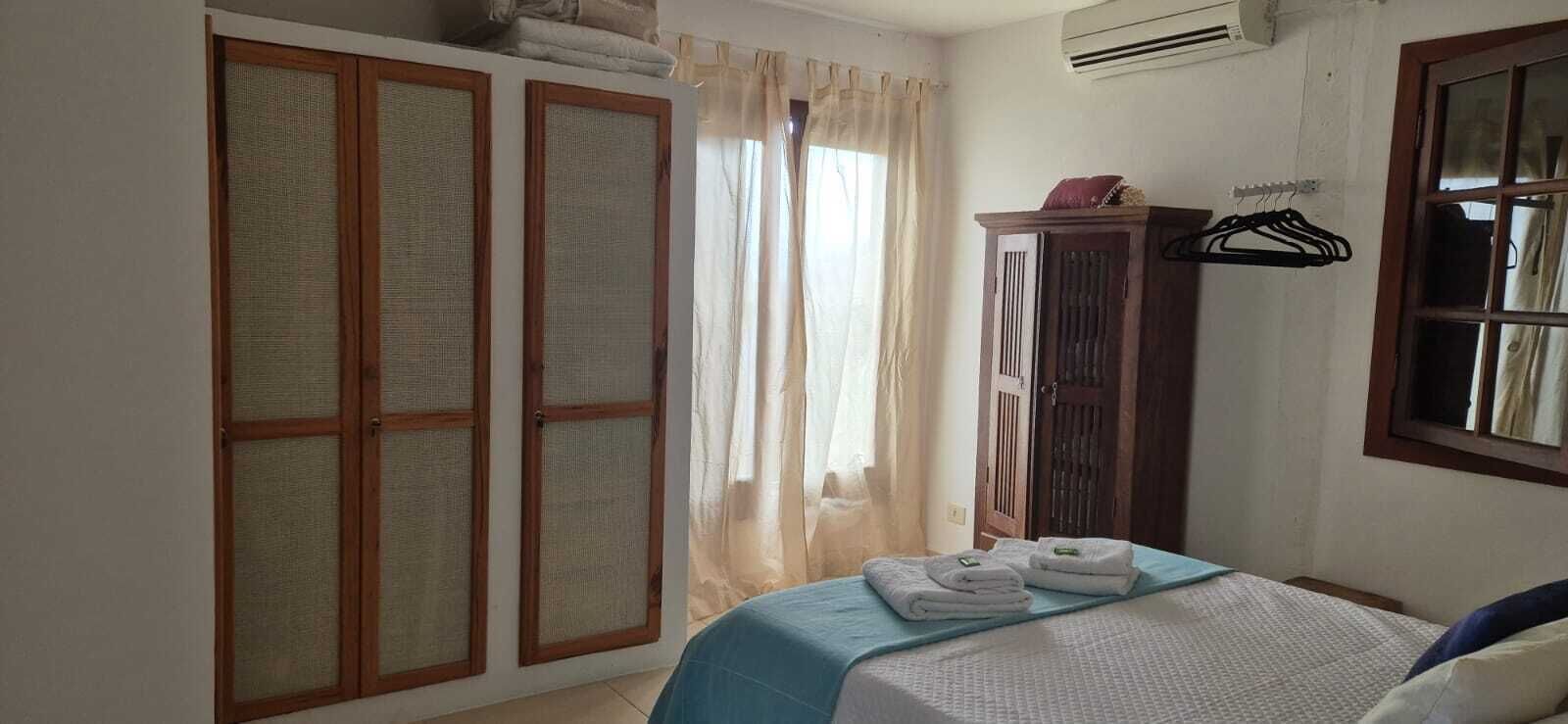 A bedroom with a bed, a wardrobe, a window with curtains, and a radiator.