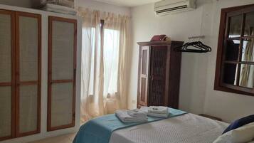 A bedroom with a bed, a wardrobe, a window with curtains, and a radiator.