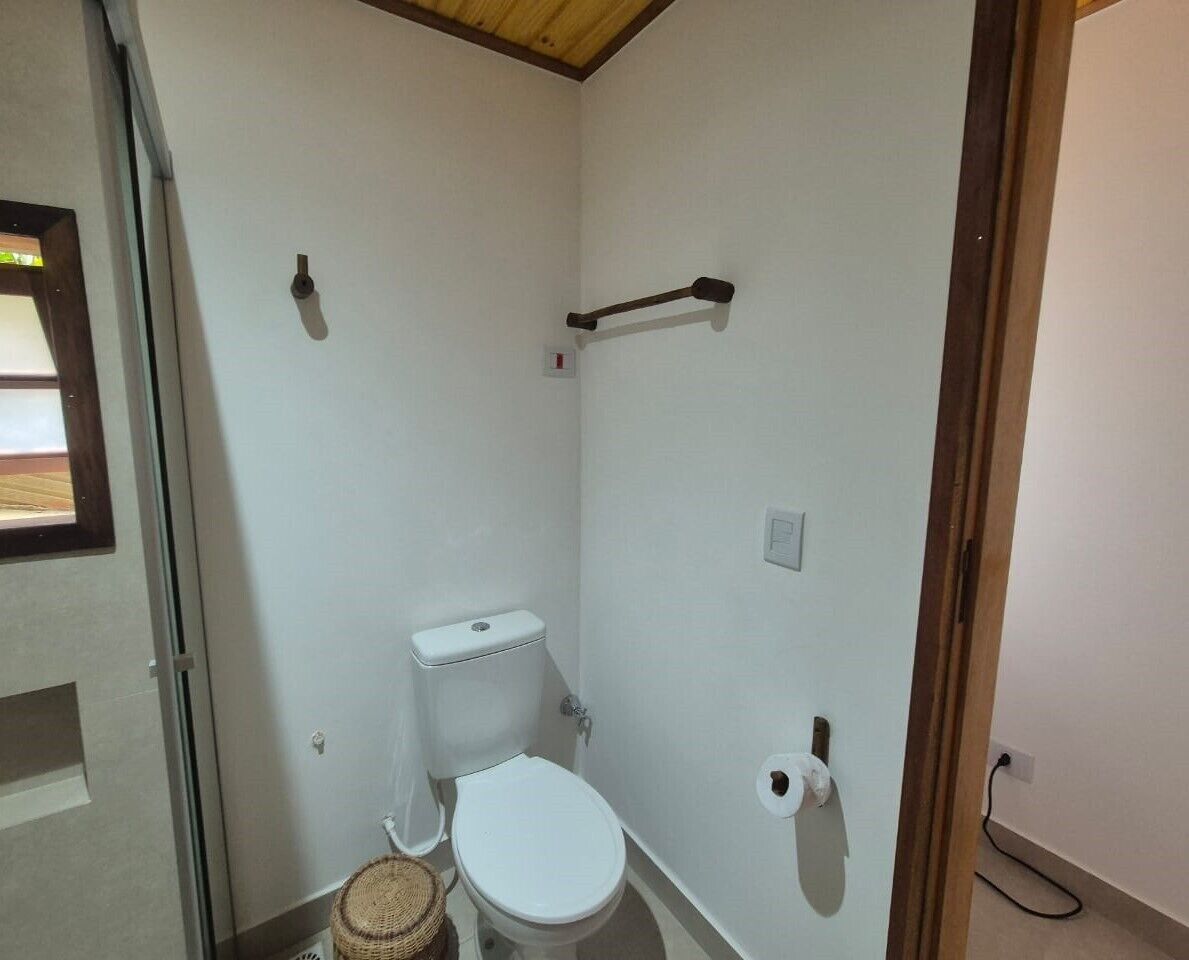 A small, compact bathroom with a toilet, a bidet, and a toilet paper holder.