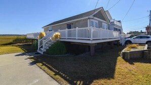 A two-story house with a front deck and a staircase leading to the entrance. - Reeds beach retreat 2 bedroom with water view (Reeds Beach)