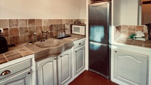 A kitchen with white cabinets, a stainless steel refrigerator, a microwave, and a hanging light fixture.