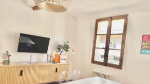 A modern room with a wooden reception desk, a flat-screen TV, a potted plant, and a window with a view.
