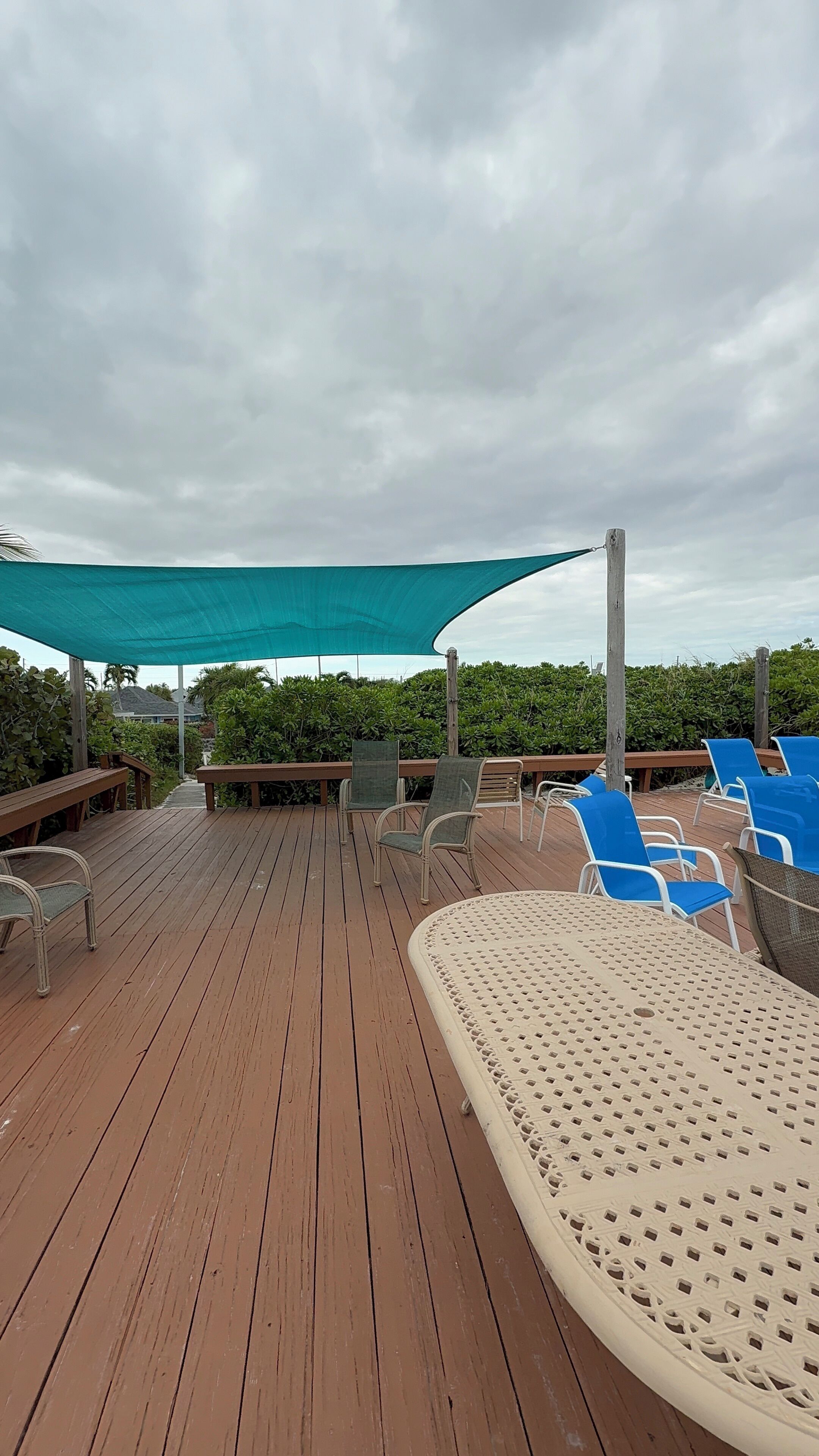 A wooden deck with lounge chairs and a table under a canopy.
