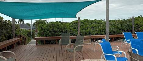 A wooden deck with lounge chairs and a table under a canopy.
