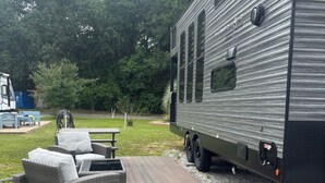 A recreational vehicle with a deck and outdoor furniture. - Timberwolf in the Park (Pensacola)