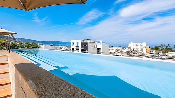 Ein Dachpool mit Infinity-Kante und freiem Blick auf Gebäude und Berge im Hintergrund.