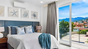 Ein modernes Schlafzimmer mit einem großen Bett, Blick auf eine Stadtlandschaft und Kunstwerken an der Wand.