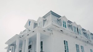 Un edificio blanco con un tejado pronunciado y numerosas ventanas.