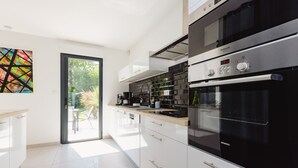 Una cocina moderna con armarios blancos, un horno negro y un reloj digital.