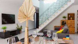 Una sala de estar moderna con una escalera de cristal, un televisor de pantalla plana y un sofá con cojines de colores.
