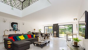 Una sala de estar moderna con un sofá seccional gris, una mesa de centro y un comedor con una mesa y sillas.