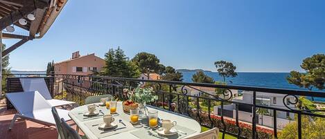Ein Balkon mit Frühstückstisch und Blick auf die Küste.