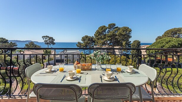 A table set for two with a view of the sea, surrounded by metal chairs and a railing. - Beau Rivage - 7min à pied de la Plage (Carqueiranne)