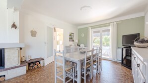 A spacious kitchen with a dining area, a fireplace, and a television. - Lou Vaou - Maison Climatisée avec Piscine (Carcès)