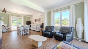 A spacious living area with a dining table, two leather chairs, a bench, and a TV. - Lou Vaou - Maison Climatisée avec Piscine (Carcès)