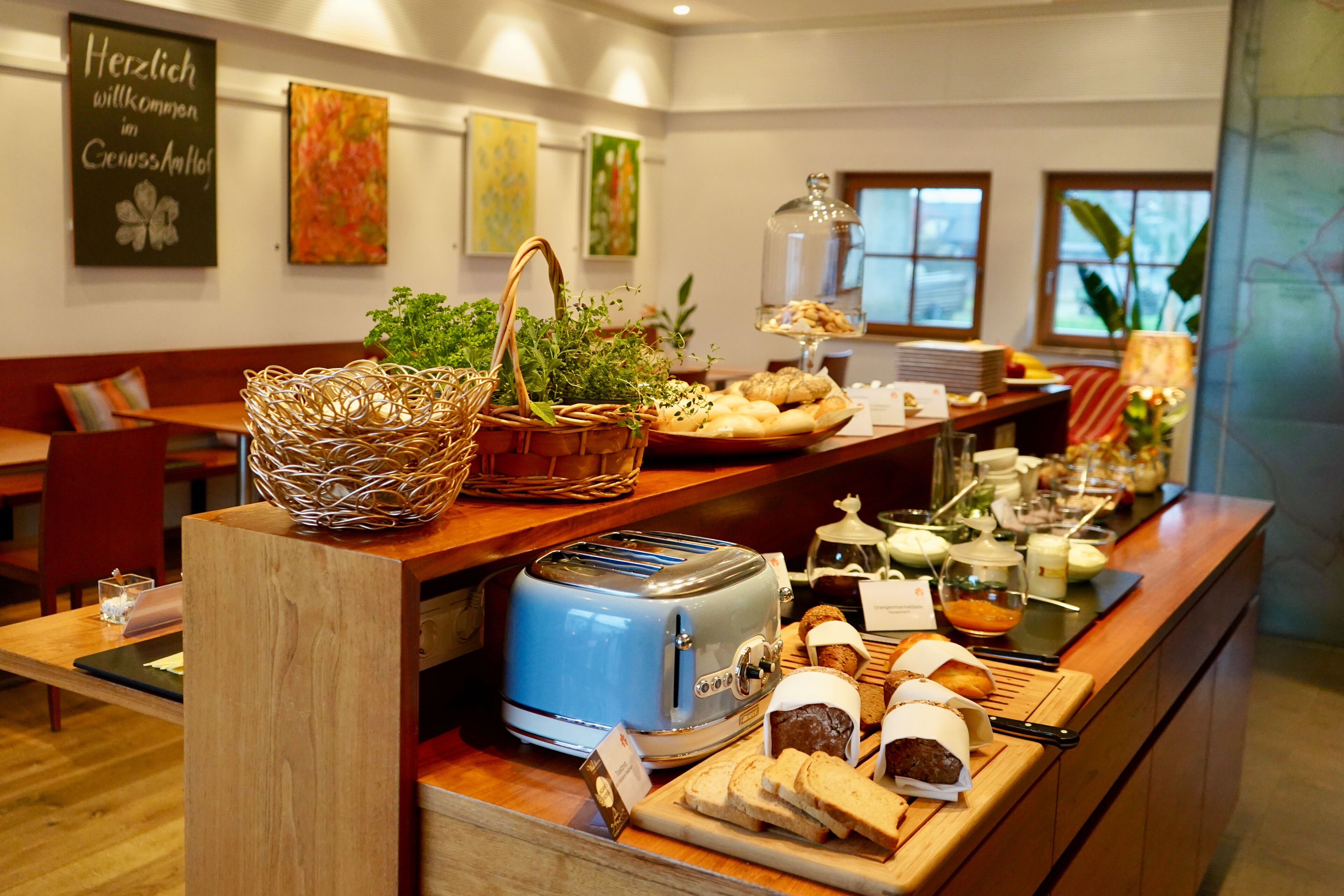A breakfast buffet with various breads, pastries, and a toaster.