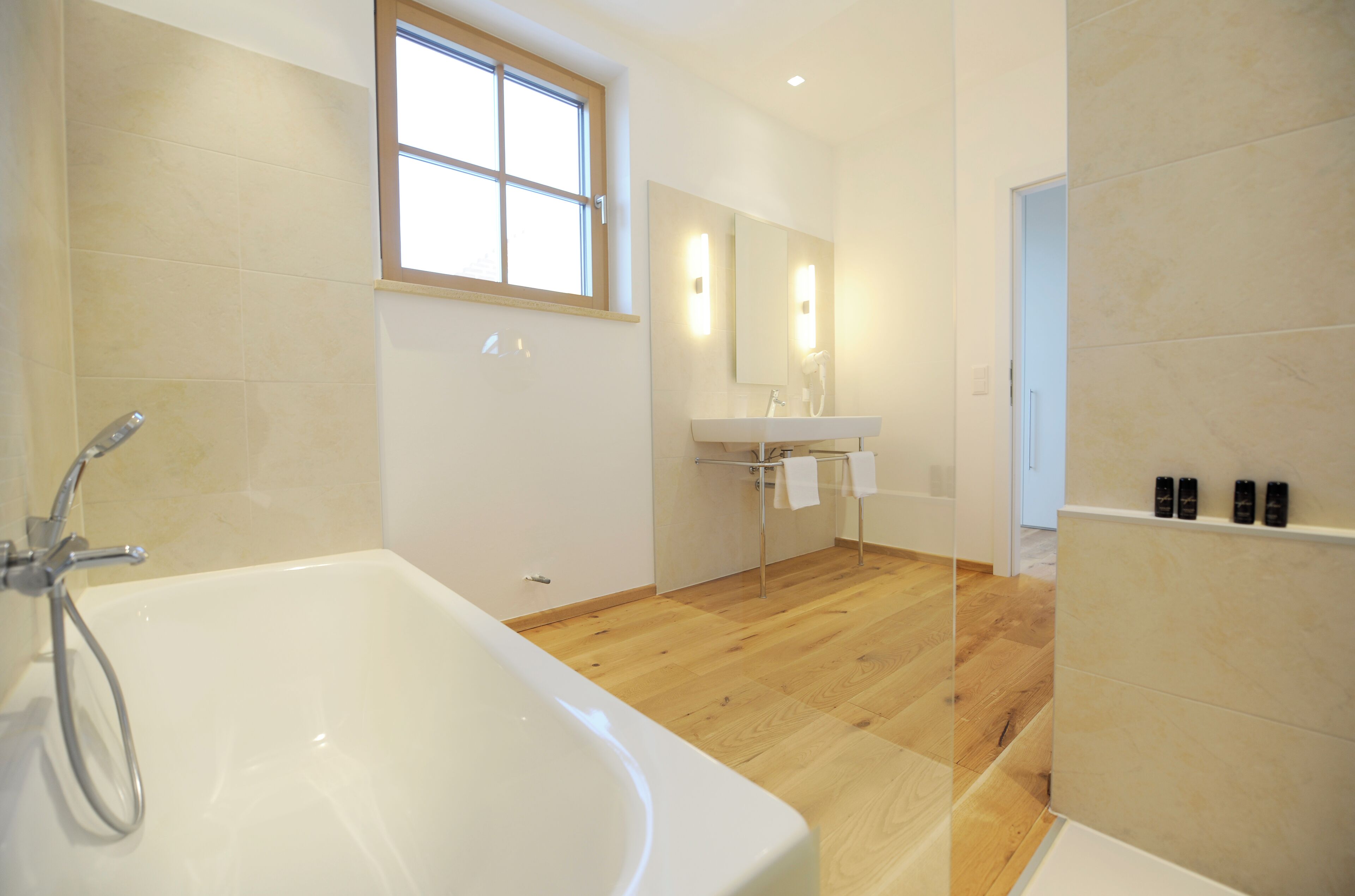 Un baño moderno con bañera, lavamanos y espejo.