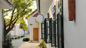 A narrow cobblestone path leading to a building with a wooden door and a window with a black frame. - Hotel Genuss am Hof (Halbturn)