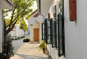 Un estrecho sendero empedrado que conduce a un edificio con puerta de madera y ventana de marco negro.