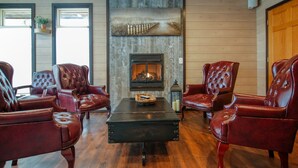 Una habitación con chimenea, sillones de cuero y suelo de madera.