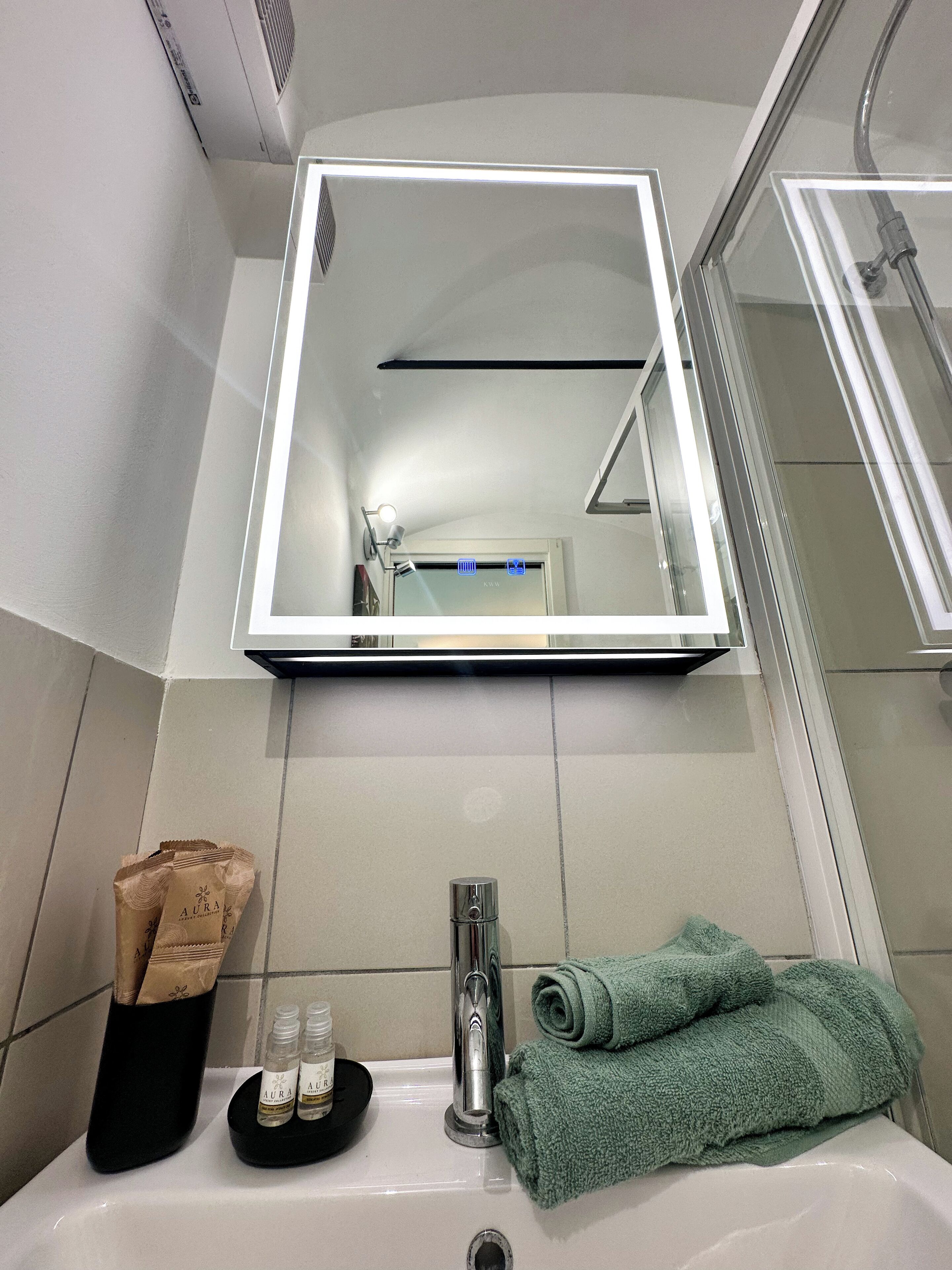 A bathroom with a mirror, sink, and toiletries.