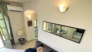 Ein modernes Wohnzimmer mit einem grauen Sofa, einem runden Couchtisch und einer Topfpflanze.