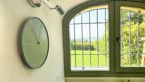 Eine Küche mit einer Uhr, einem Fenster mit Blick auf Grünflächen und einem Herd.