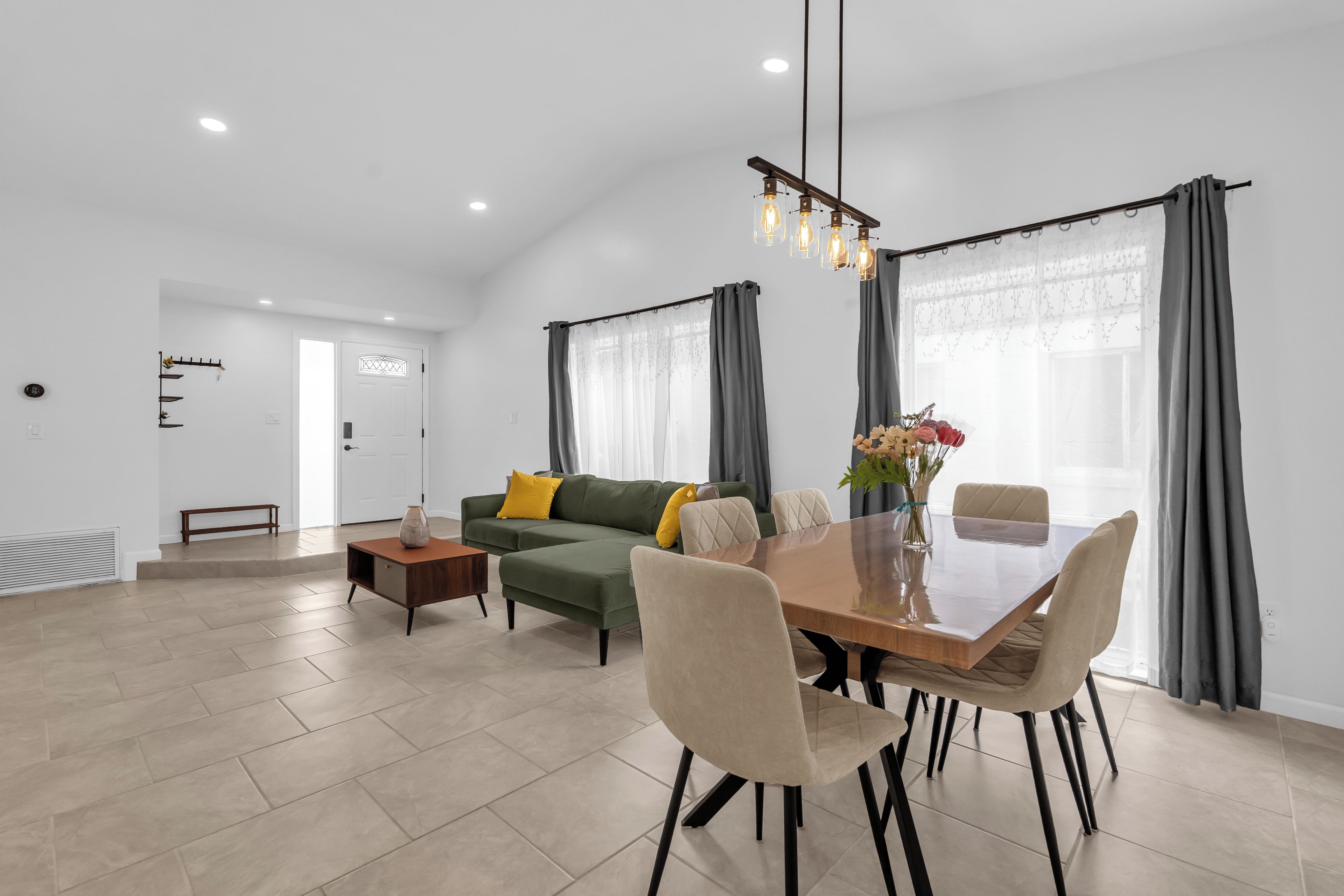 Una sala de estar moderna con zona de comedor, que incluye un sofá, una mesa de centro y una mesa de comedor con sillas.